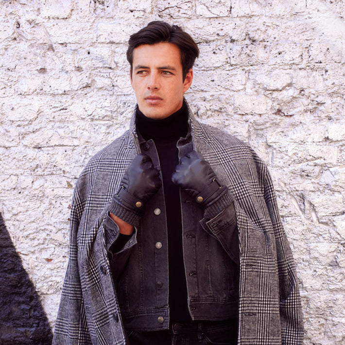 Man wearing black leather gloves and a coat in the city