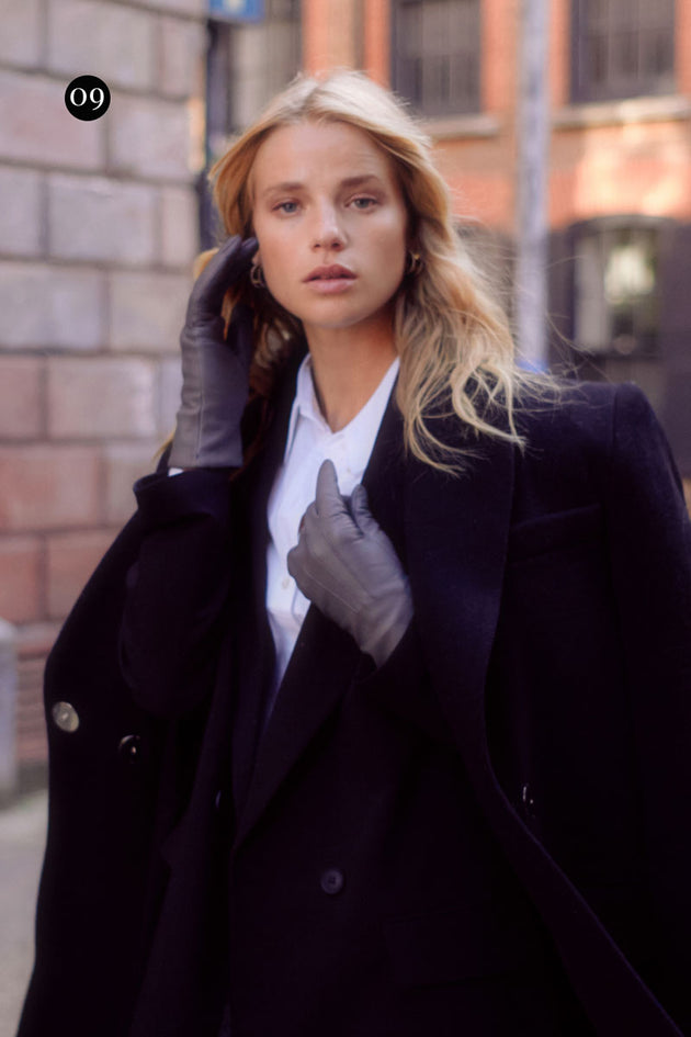 Woman wearing grey leather gloves with a blazer in the city