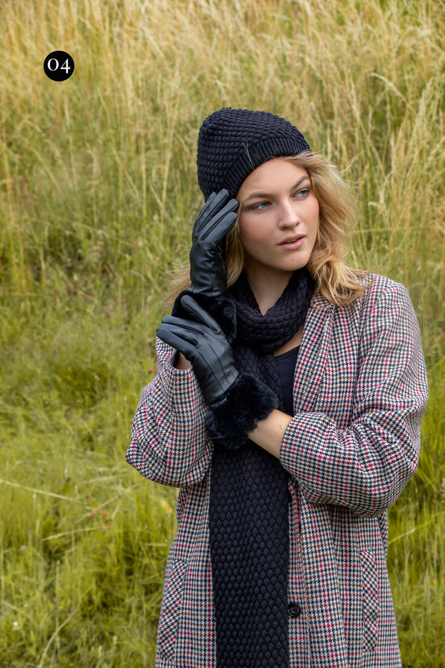 Woman wearing black knitted hat, scarf and gloves in the park