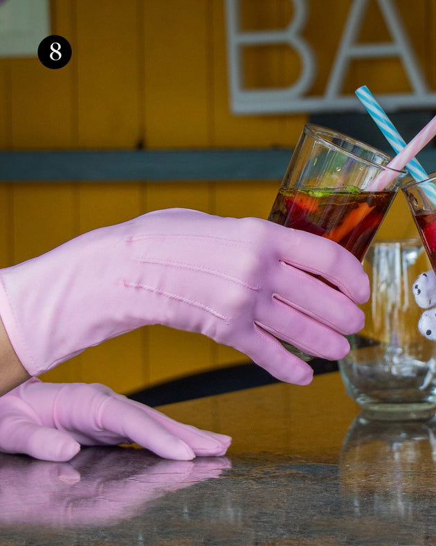 Woman wearing matt satin gloves in pale pink holding a glass