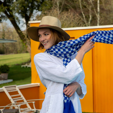 Woman wearing check scarf in blue with a straw hat on holiday