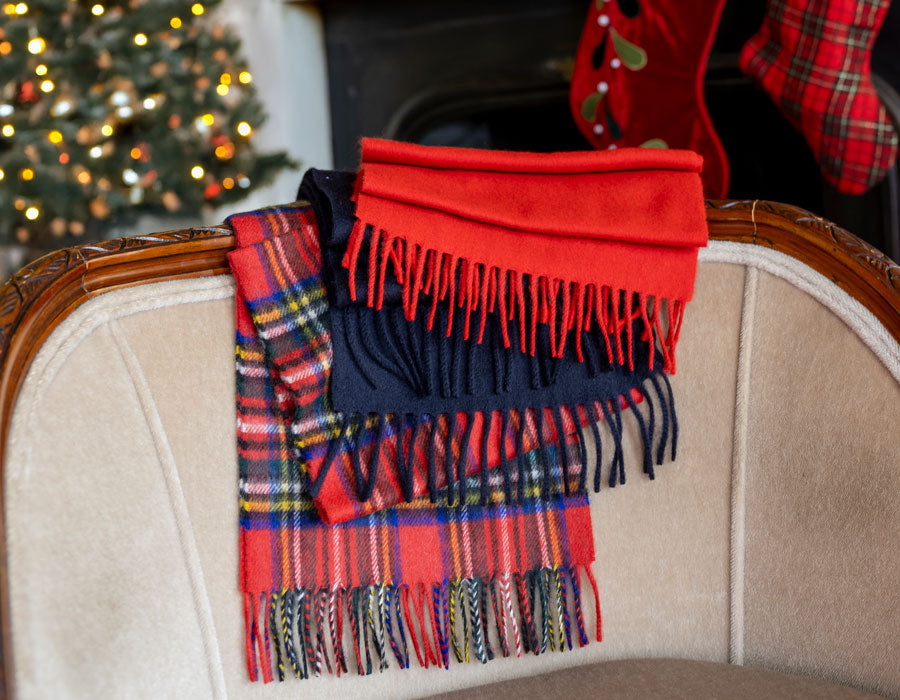 MEN'S AND WOMEN'S CASHMERE SCARVES IN VARIOUS COLOURS ON SOFA WITH A CHRISTMASSY BACKGROUND