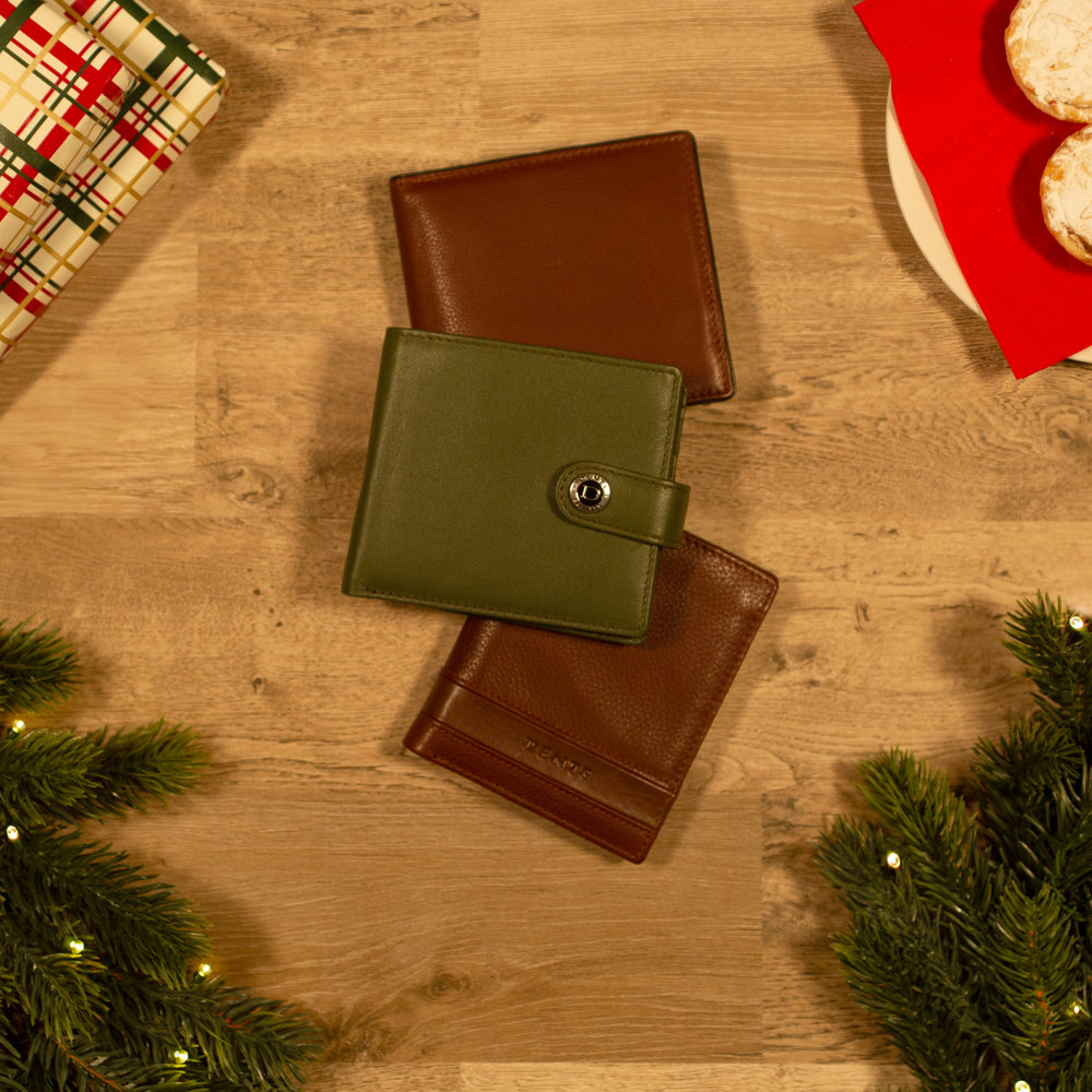 Selection of green and brown leather men's wallets against a wooden background with Christmas accessories