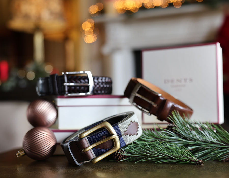 MEN'S LEATHER BELTS IN VARIOUS COLOURS ON TABLE WITH A CHRISTMASSY BACKGROUND