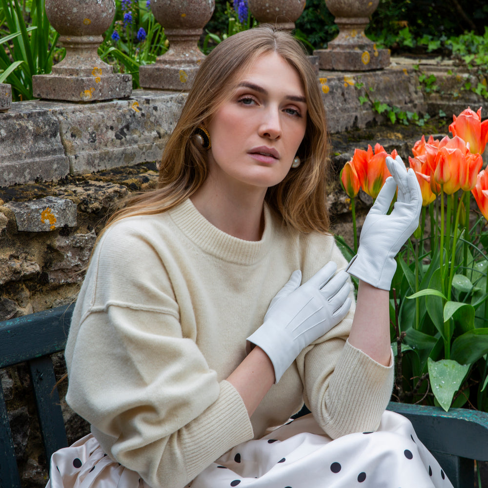 Woman wearing white leather gloves sat on a park bench