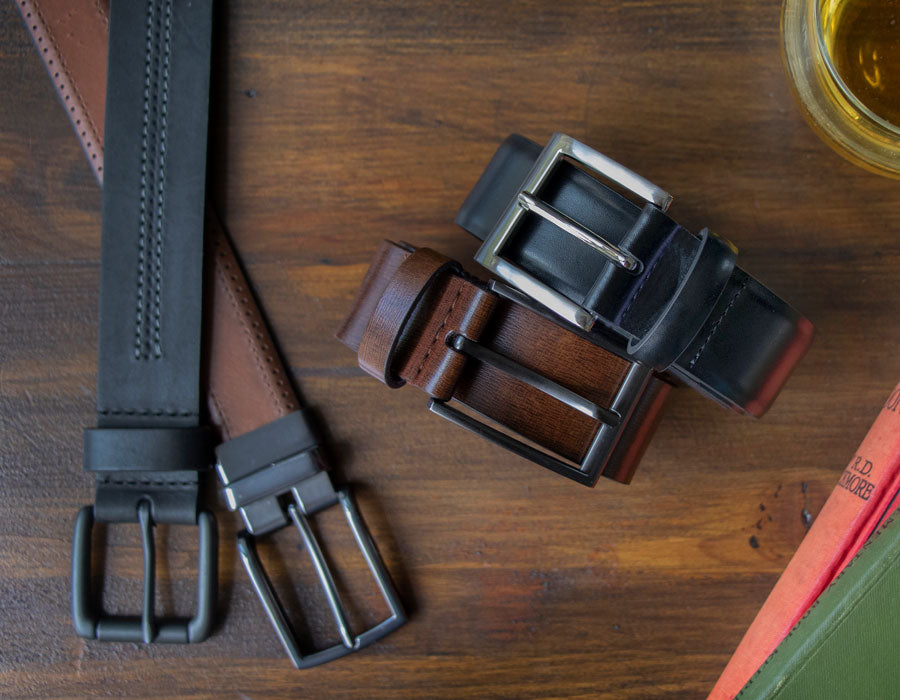 Men's leather belts in various styles and colours on a wooden table
