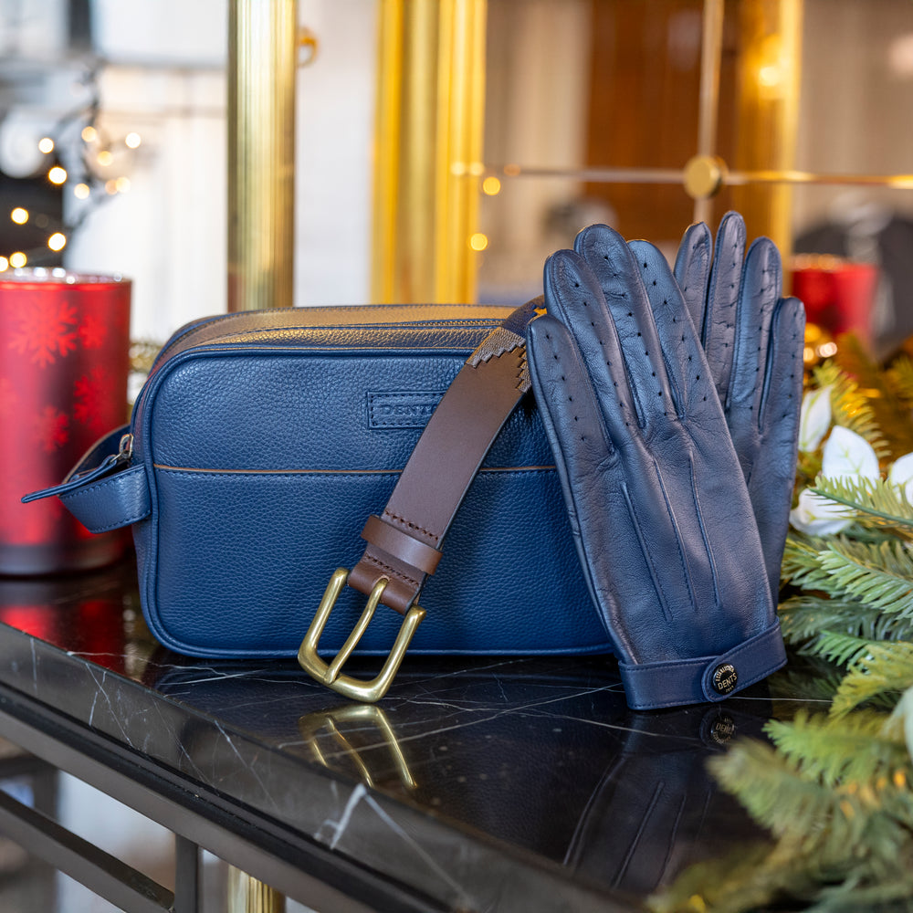Men's blue leather driving gloves, wash bag and belt on a festive table with Christmas background