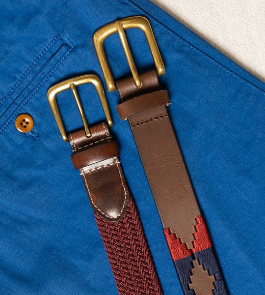 Men's belts in various colours and styles on a blue linen background