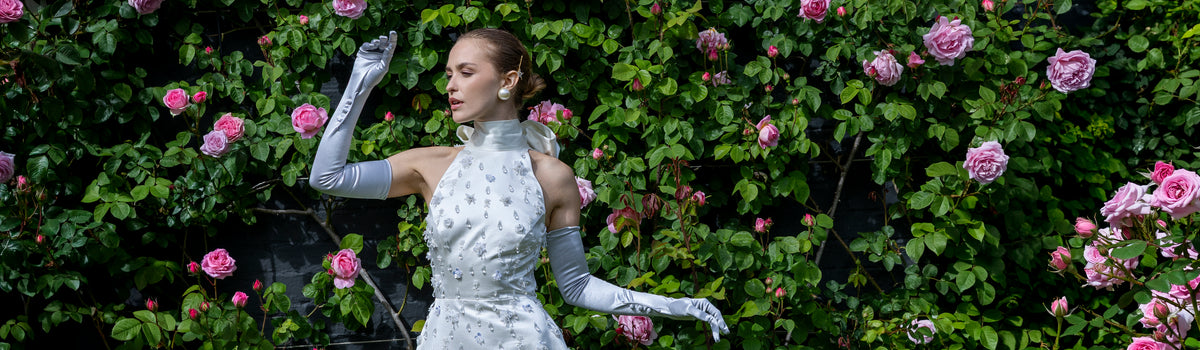 Woman wearing long satin gloves with buttons in silver with a white bejelewed dress outdoors