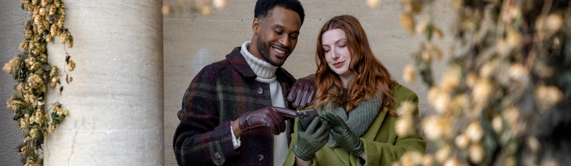 Man and woman wearing leather gloves in various colours using a mobile phone outdoors
