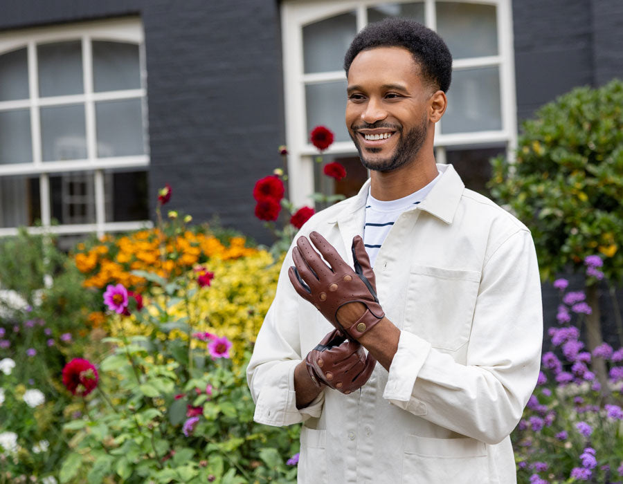 Man wearing brown leather driving gloves with linen jacket outdoors
