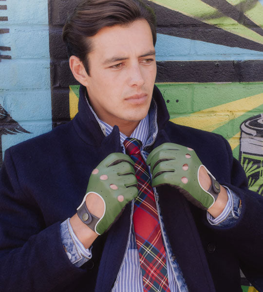 Man wearing leather driving gloves in green with a lightweight coat 