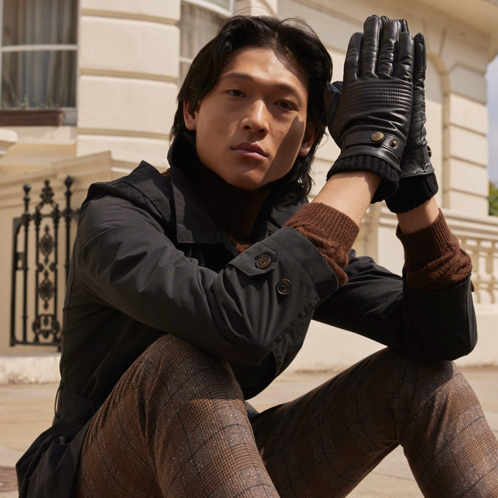 Man wearing leather gloves sat on a curb in the city