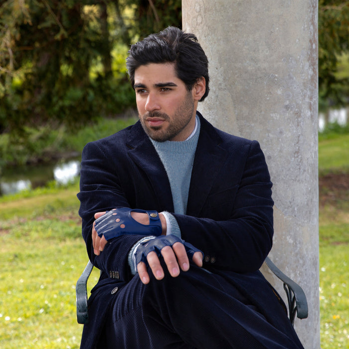 Man wearing royal blue leather fingerless driving gloves sitting in the park