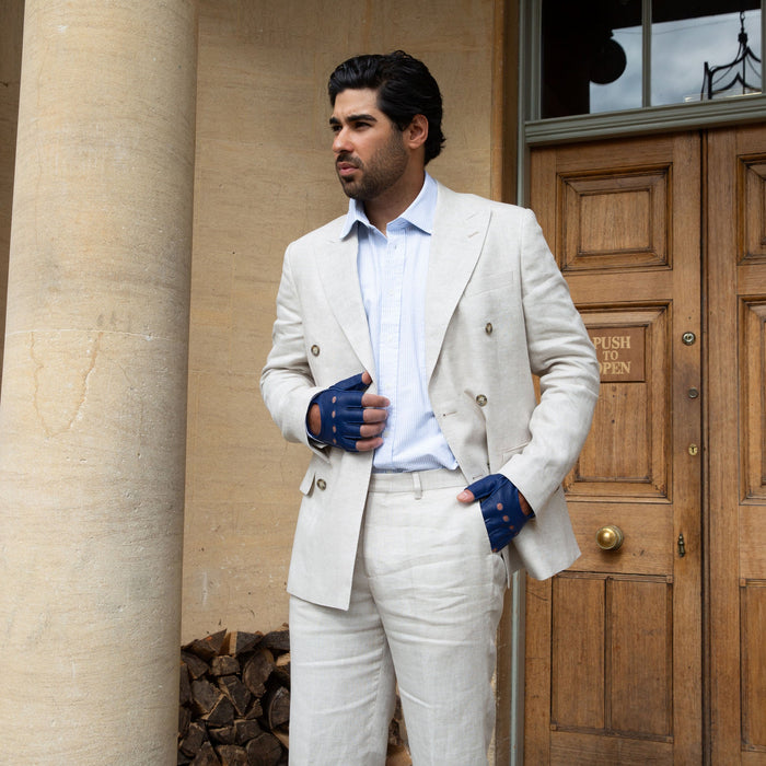 Man wearing royal blue leather fingerless driving gloves standing by a grand door