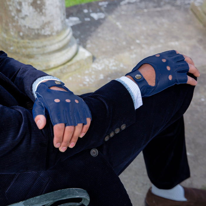 Man wearing royal blue leather fingerless driving gloves sitting in the park closeup of hands