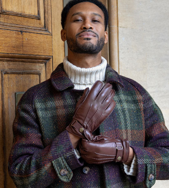 Man wearing three-point, lined heritage leather gloves in brown with winter coat.