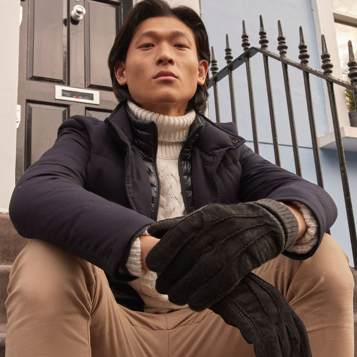 Man wearing Men's Three Point Fleece Lined Suede Gloves Black Charcoal sitting on some stairs