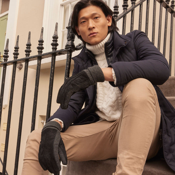 Man wearing Men's Three Point Fleece Lined Suede Gloves Black Charcoal sitting on some stairs