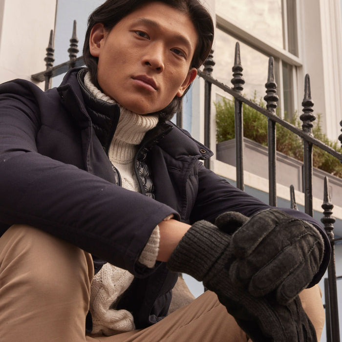 Man wearing Men's Three Point Fleece Lined Suede Gloves Black Charcoal sitting on some stairs