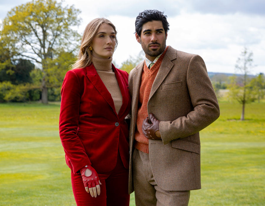 A man and a woman wearing leather driving gloves at a grand home