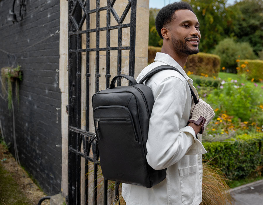 Man wearing driving gloves and leather backpack in black outdoors