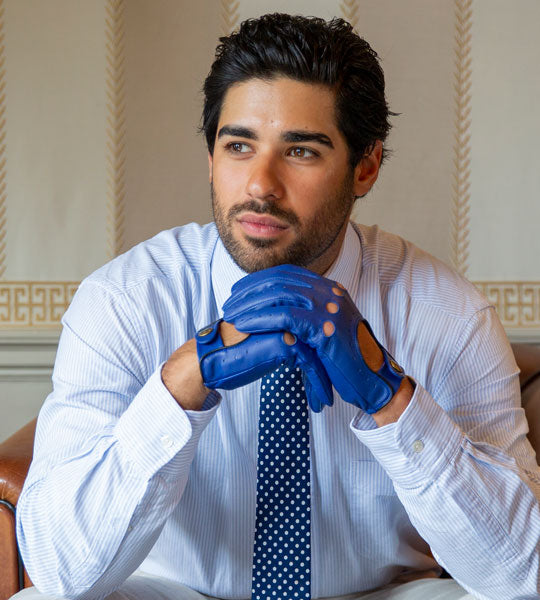 Man wearing blue leather driving gloves sitting indoors
