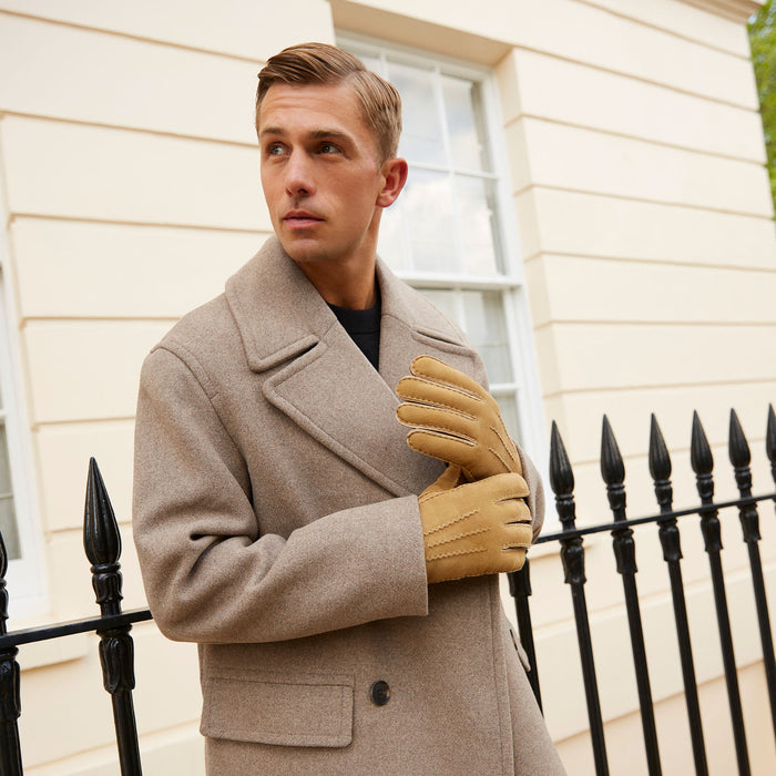 Man wearing handsewn lambskin gloves in camel and wool trench coat in the city