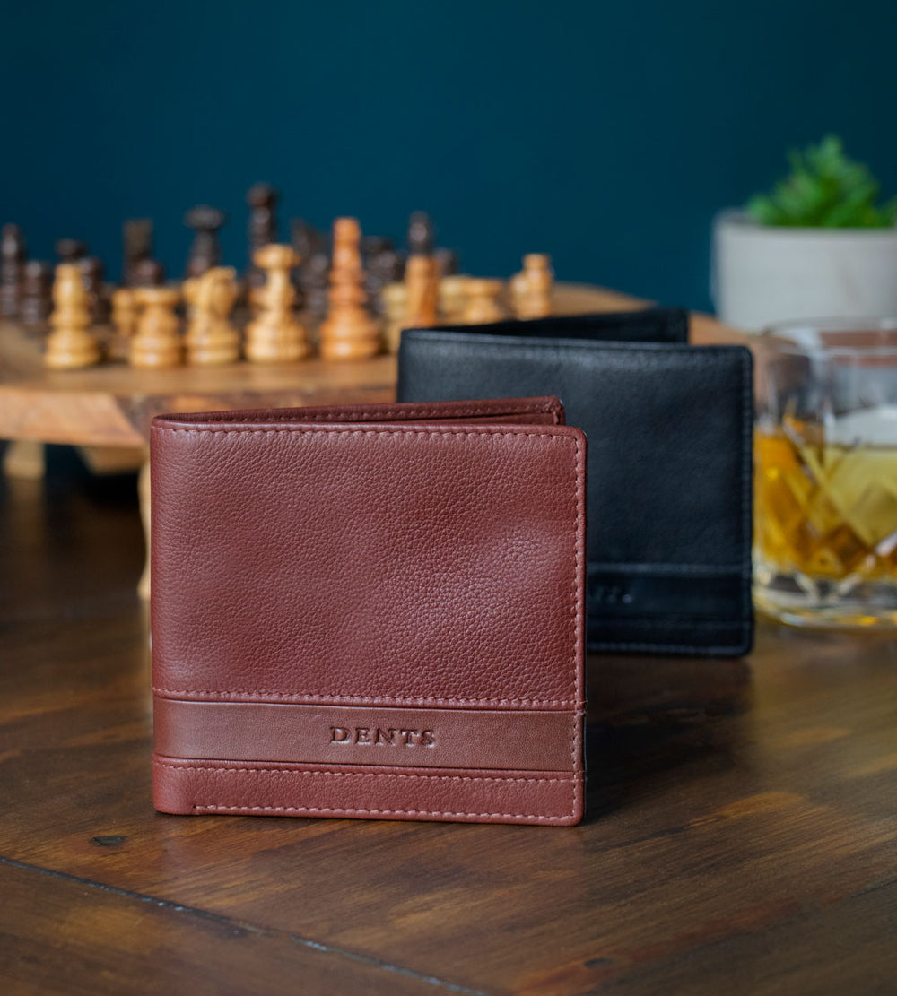 Two men's wallets in brown and black on a table with a chess board