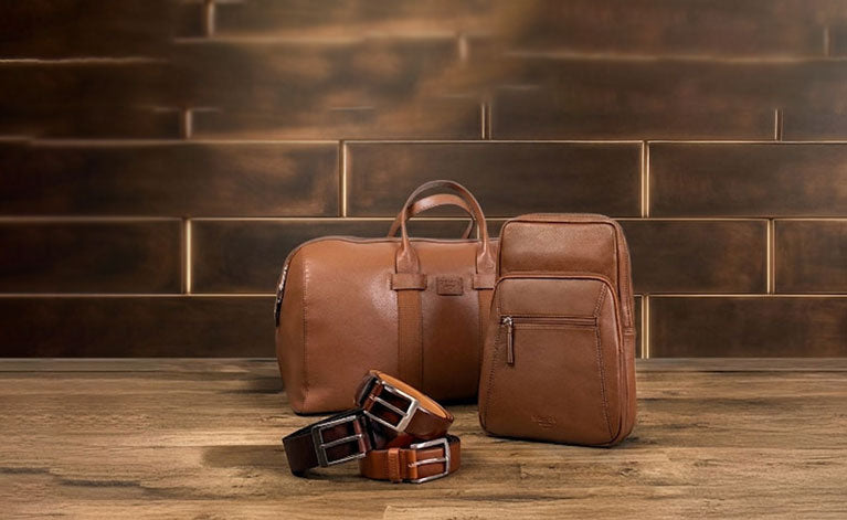 Men's leather bags and belts in various brown colours on a wooden and stone background