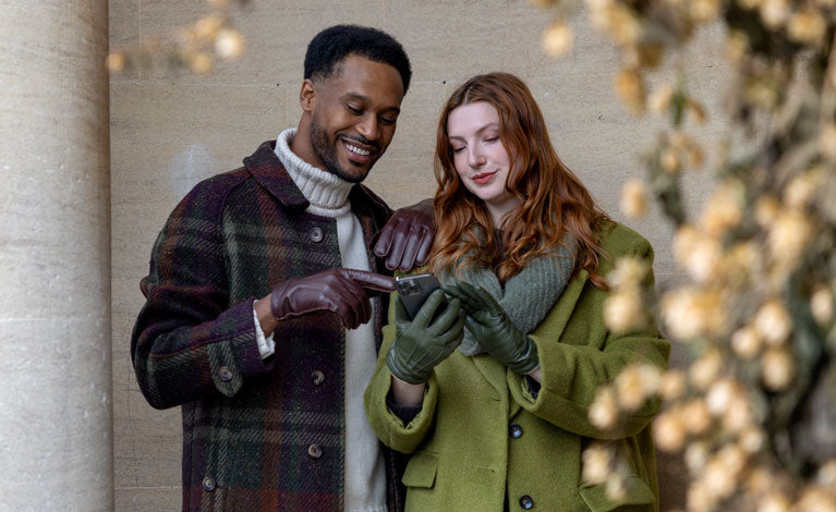 Man and woman wearing leather gloves using a mobile phone 