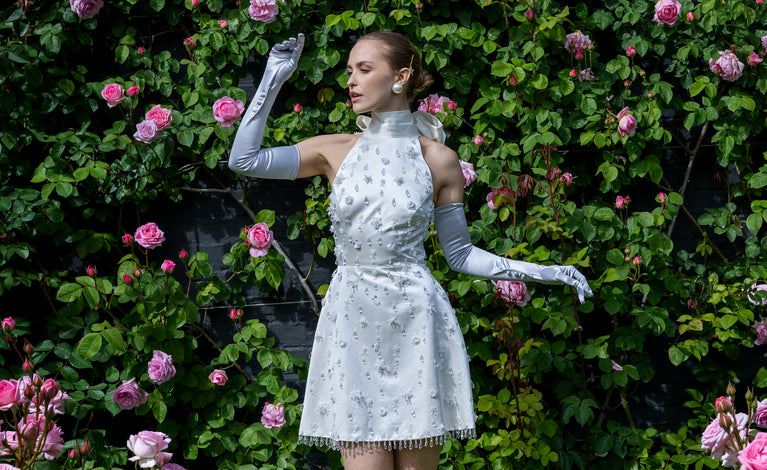 Woman wearing long satin gloves with buttons in silver with a white bejelewed dress outdoors
