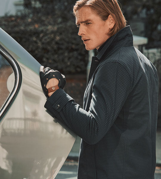 man wearing leather driving gloves in black opening a boot of a car