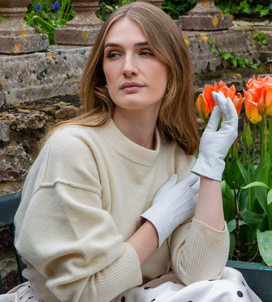 Woman wearing leather gloves in silver sitting on a bench at the park