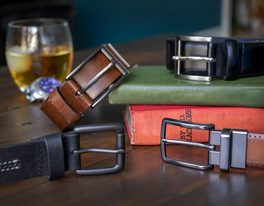 Various men's leather belts resting on books. 