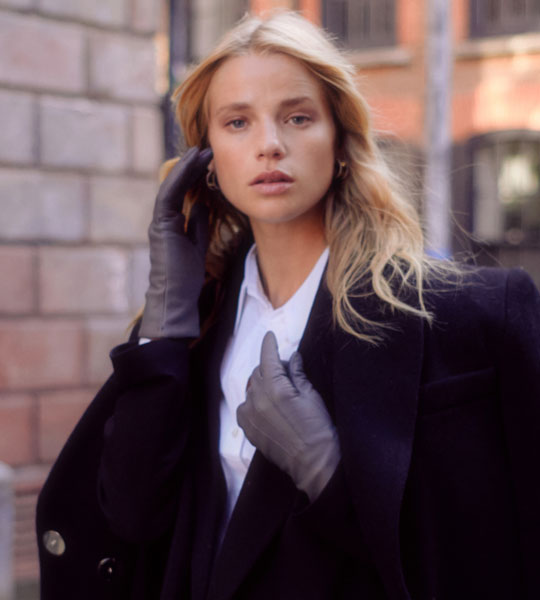 Woman wearing three-point lined leather gloves in grey in the street.