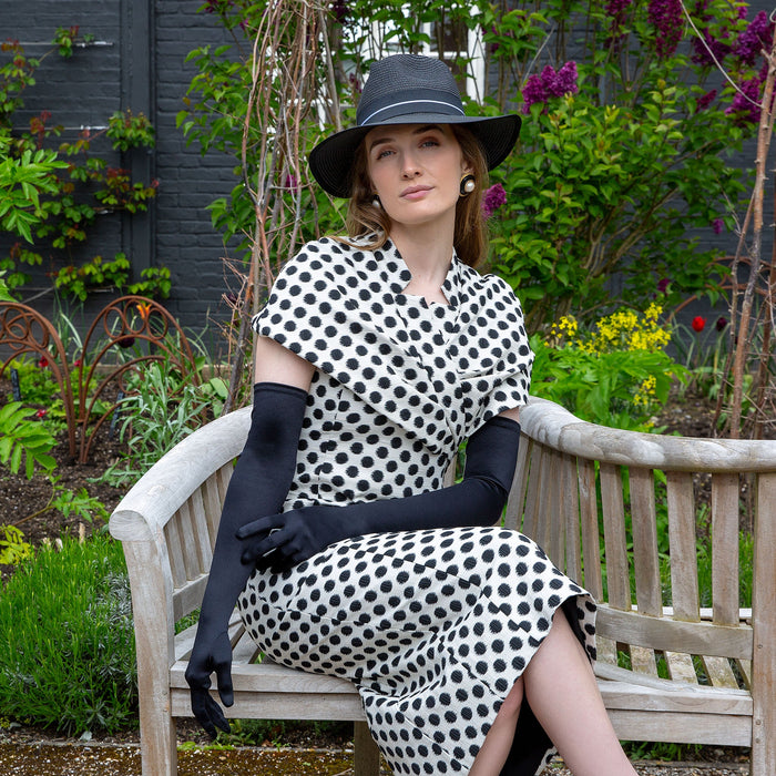 woman wearing long opera satin gloves in black with straw hat