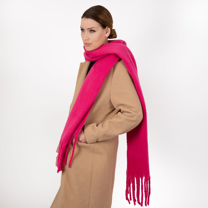 Woman wearing blanket scarf with tassels in fuchsia 