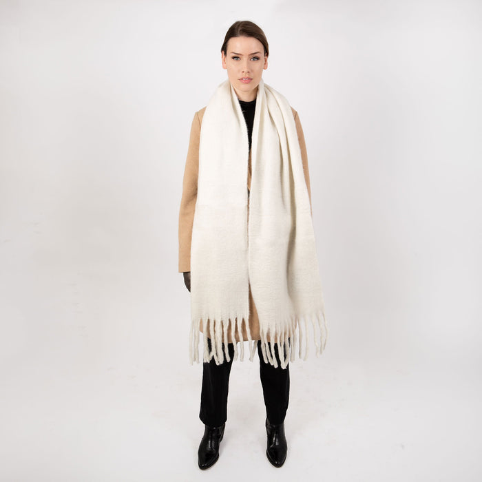 Woman wearing blanket scarf with tassels in ivory