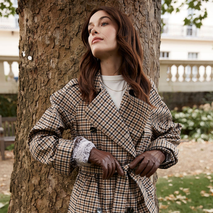 Woman wearing leather touchscreen gloves with faux fur cuffs in chestnut at the park