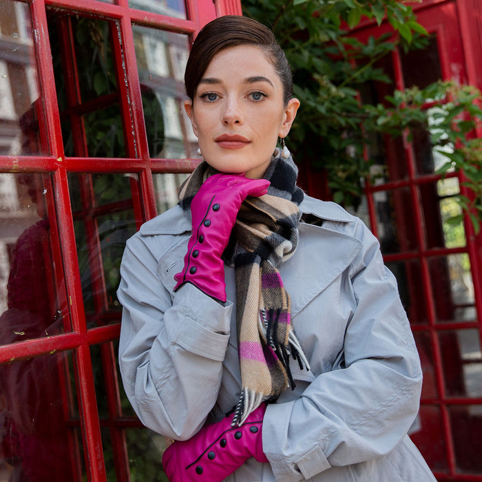 woman wearing pink leather gloves with black piping and buttons