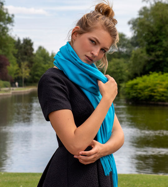 Woman wearing a pashmina scarf in blue on a walk in the park