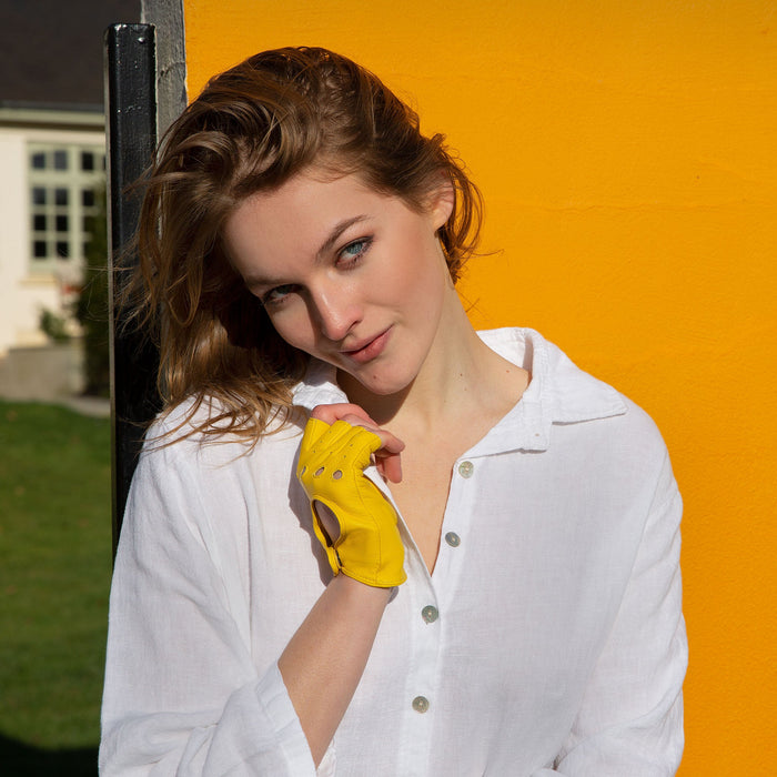 Woman wearing yellow fingerless leather gloves and a white shirt on holiday